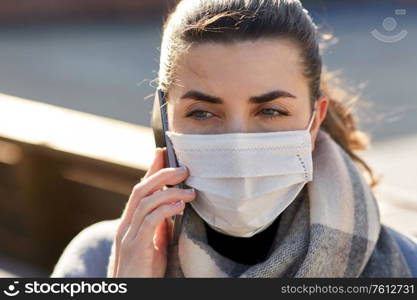 health, safety and pandemic concept - young woman wearing protective medical mask and calling on smartphone on city street. woman in face mask calling on smartphone in city