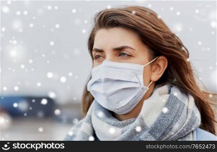 health, safety and pandemic concept - young woman wearing protective medical mask outdoors in winter over snow. young woman wearing protective medical mask