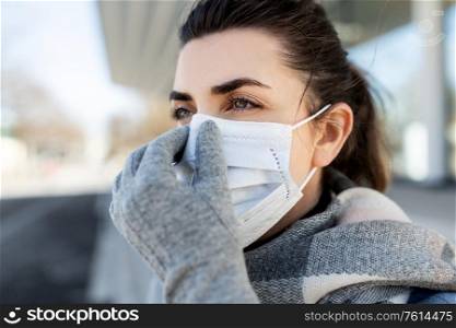 health, safety and pandemic concept - young woman wearing protective medical mask in city. woman wearing protective medical mask in city