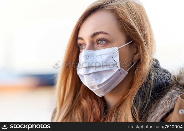 health, safety and pandemic concept - young woman wearing protective medical mask outdoors. young woman wearing protective medical mask