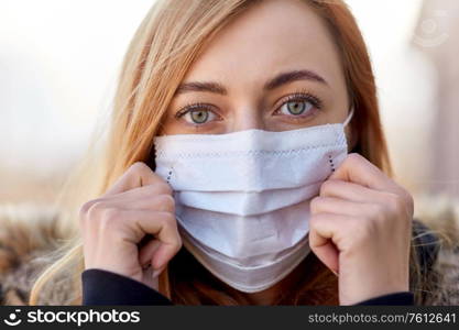 health, safety and pandemic concept - young woman wearing protective medical mask outdoors. young woman wearing protective medical mask