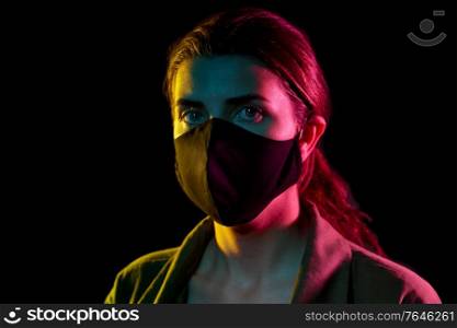 health, safety and pandemic concept - young woman wearing reusable protective mask over black background. young woman wearing reusable protective mask
