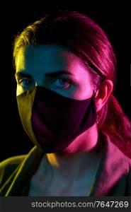 health, safety and pandemic concept - young woman wearing reusable protective mask over black background. young woman wearing reusable protective mask