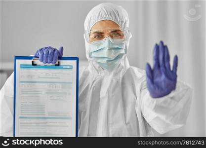 health safety, medicine and pandemic concept - close up of female doctor or scientist in protective wear, medical mask and goggles showing medical report on clipboard and stop gesture. doctor in medical mask and goggles with clipboard