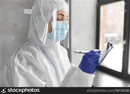 health safety, medicine and pandemic concept - close up of female doctor or scientist in protective wear, medical mask, gloves and face shield for protection from virus disease with clipboard. doctor in medical mask and shield with clipboard