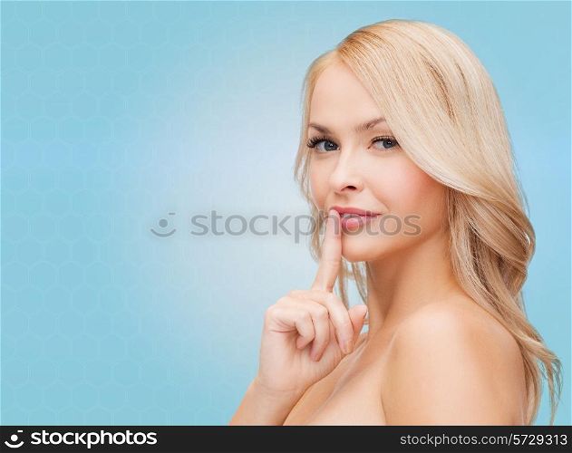 health, secret, people and beauty concept - clean face of beautiful young woman pointing finger to her lips over blue background