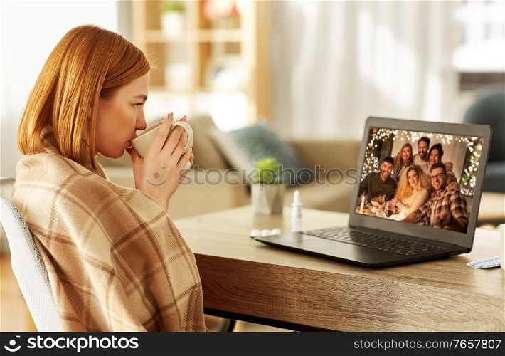 health, social distancing and technology concept - sick young woman having video call with her friends on laptop computer and drinking tea at home on christmas. sick woman having video call with friends at home