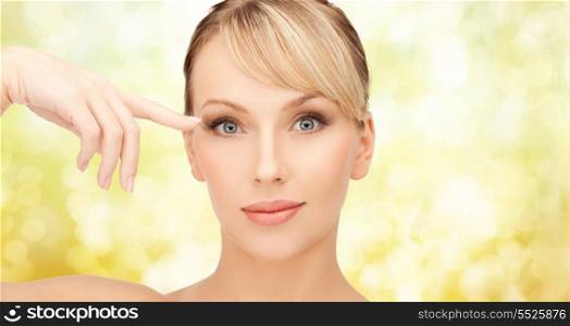 health, spa and beauty concept - beautiful woman touching her eye area