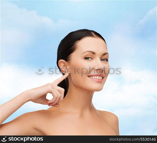 health, spa and beauty concept - clean face of beautiful young woman pointing to her ear