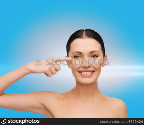 health, spa and beauty concept - clean face of beautiful young woman pointing to her eye