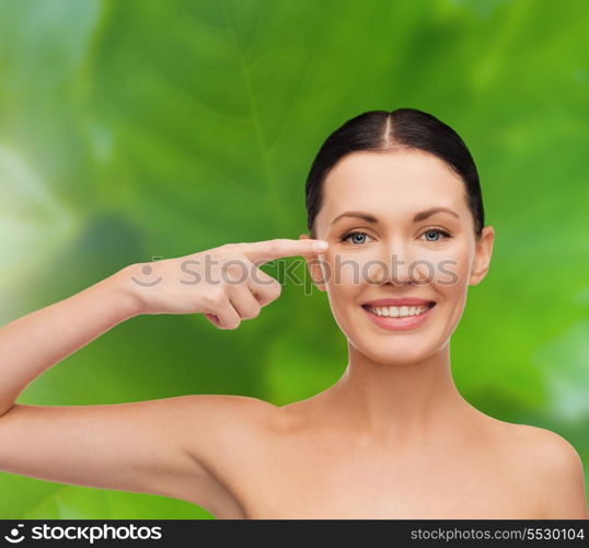 health, spa and beauty concept - clean face of beautiful young woman pointing to her eye