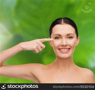 health, spa and beauty concept - clean face of beautiful young woman pointing to her eye