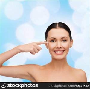 health, spa and beauty concept - clean face of beautiful young woman pointing to her eye
