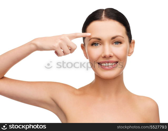 health, spa and beauty concept - clean face of beautiful young woman pointing to her forehead