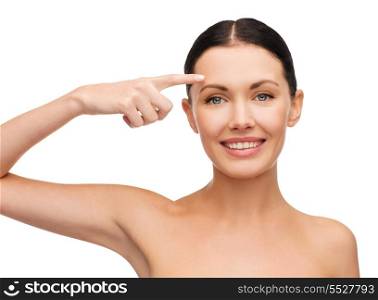 health, spa and beauty concept - clean face of beautiful young woman pointing to her forehead