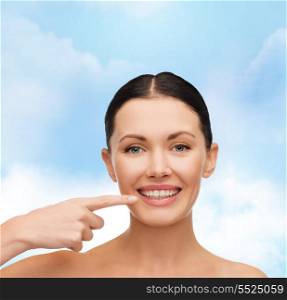 health, spa and beauty concept - clean face of beautiful young woman pointing to her mouth