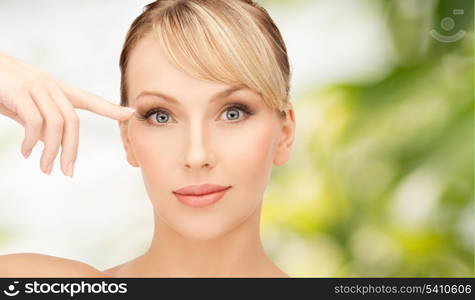 health, spa and beauty concept - face of beautiful woman touching her eye area