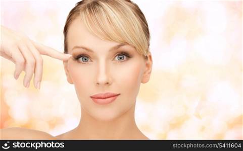 health, spa and beauty concept - face of beautiful woman touching her eye area