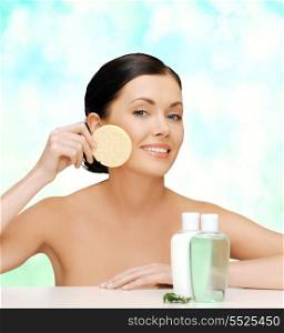 health, spa and beauty concept - picture of woman with sponge and cosmetic bottles