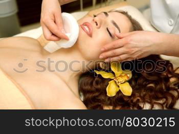 Health spa: close-up of a beautiful relaxing woman having facial massage with a talcom powder