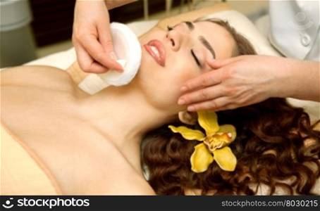 Health spa: close-up of a beautiful relaxing woman having facial massage with a talcom powder