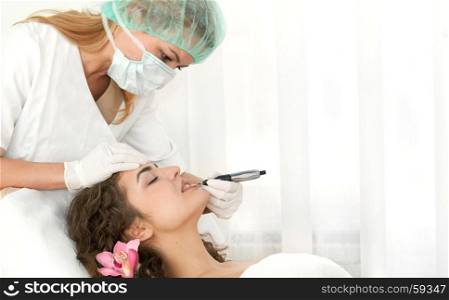 Health spa: close-up of beautiful relaxing young woman having facial massage (electrolysis), with orchid in long brown hair.