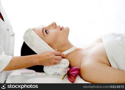 Health spa: close-up of beautiful relaxing young woman having facial massage (electrolysis), with orchid in long brown hair.