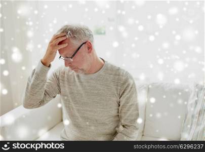 health, stress and people concept - senior man suffering from headache at home over snow. senior man suffering from headache at home