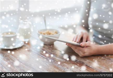 health, technology, internet, food and home concept - close up of woman with tablet pc computer screen sitting at table and having breakfast