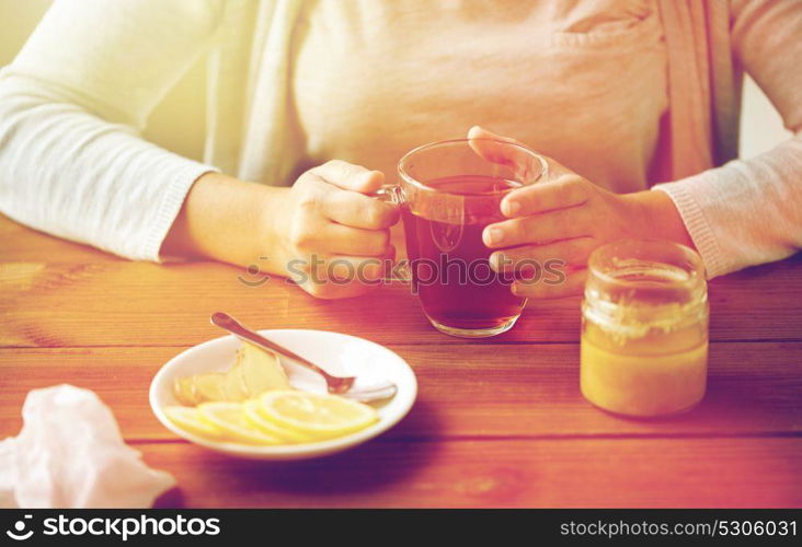 health, traditional medicine and ethnoscience concept - close up of woman adding lemon to tea cup. close up of woman adding lemon to tea cup