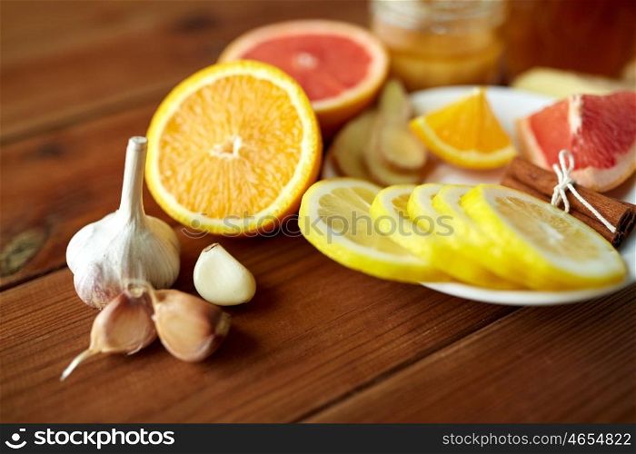 health, traditional medicine and ethnoscience concept - garlic, lemon, orange and other folk remedy on wooden background