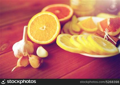 health, traditional medicine and ethnoscience concept - garlic, lemon, orange and other folk remedy on wooden background. garlic, lemon, orange and other folk remedy