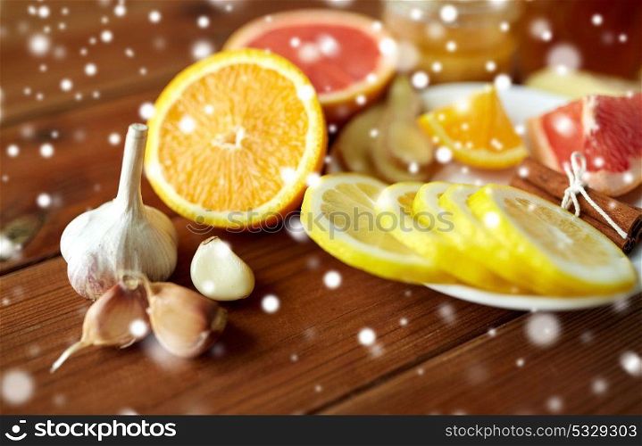 health, traditional medicine and ethnoscience concept - garlic, lemon, orange and other folk remedy on wooden background over snow. garlic, lemon, orange and other folk remedy