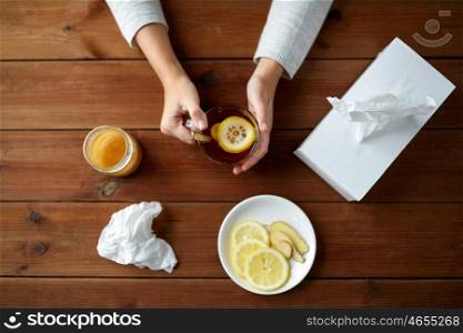 health, traditional medicine and ethnoscience concept - ill woman drinking tea with lemon, honey and ginger and paper wipes box on wooden table
