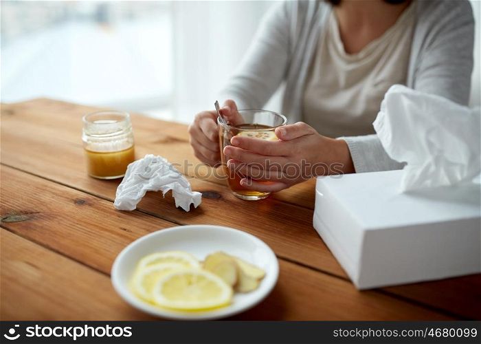 health, traditional medicine and ethnoscience concept - ill woman drinking tea with lemon and honey and paper wipes box on wooden table