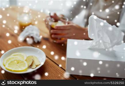 health, traditional medicine and ethnoscience concept - paper wipes box with lemon and ginger on plate over ill woman drinking tea over snow. paper wipes box with lemon and ginger on plate