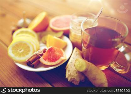 health, traditional medicine, folk remedy and ethnoscience concept - cup of ginger tea with honey, citrus and cinnamon on wooden background. ginger tea with honey, citrus and cinnamon on wood