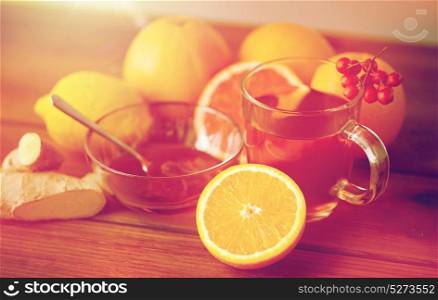 health, traditional medicine, folk remedy and ethnoscience concept - cup of tea with honey, lemon and ginger on wooden background. tea with honey, lemon and ginger on wood
