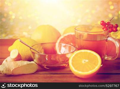 health, traditional medicine, folk remedy and ethnoscience concept - cup of tea with honey, lemon and ginger on wooden background. tea with honey, lemon and ginger on wood