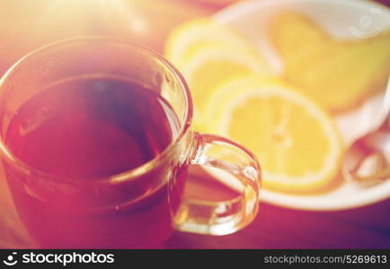 health, traditional medicine, folk remedy and ethnoscience concept - tea cup with lemon and ginger on plate with spoon. tea cup with lemon and ginger on plate