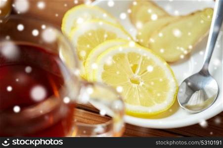 health, traditional medicine, folk remedy and ethnoscience concept - tea cup with lemon and ginger on plate with spoon over snow. tea cup with lemon and ginger on plate