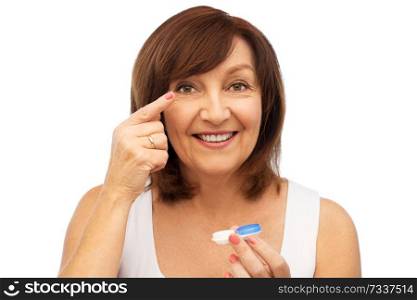 health, vision and old people concept - happy smiling senior woman putting on contact lenses over white background. happy senior woman applying contact lenses