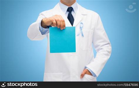 healthcare, advertisement, people and medicine concept - close up of male doctor in white coat with sky blue prostate cancer awareness ribbon holding blank paper