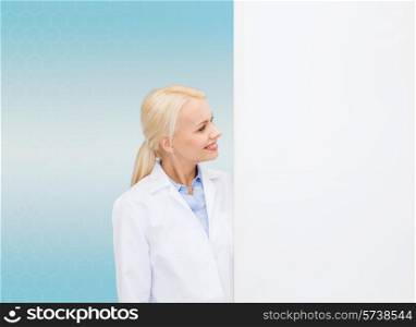 healthcare, advertisement, people and medicine concept - smiling female doctor looking to white blank board over blue background