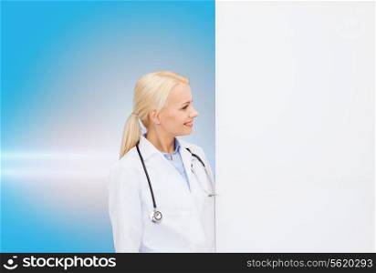 healthcare, advertisement, people and medicine concept - smiling female doctor with stethoscope looking at something over blue background