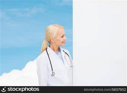 healthcare, advertisement, people and medicine concept - smiling female doctor with stethoscope looking at something over blue sky background