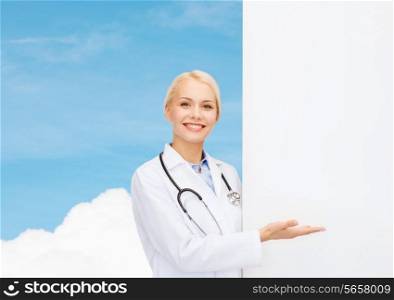 healthcare, advertisement, people and medicine concept - smiling female doctor with stethoscope showing something over blue sky background