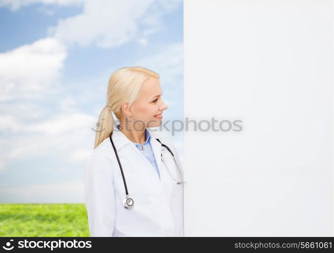 healthcare, advertisement, people and medicine concept - smiling female doctor with stethoscope looking at something over natural background