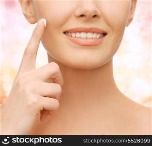 healthcare and beauty concept - beautiful woman applying moisturizing cream