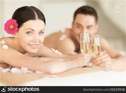 healthcare and beauty concept - picture of couple in spa salon drinking champagne